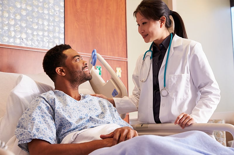 Doctor consulting patient at bedside in the hospital