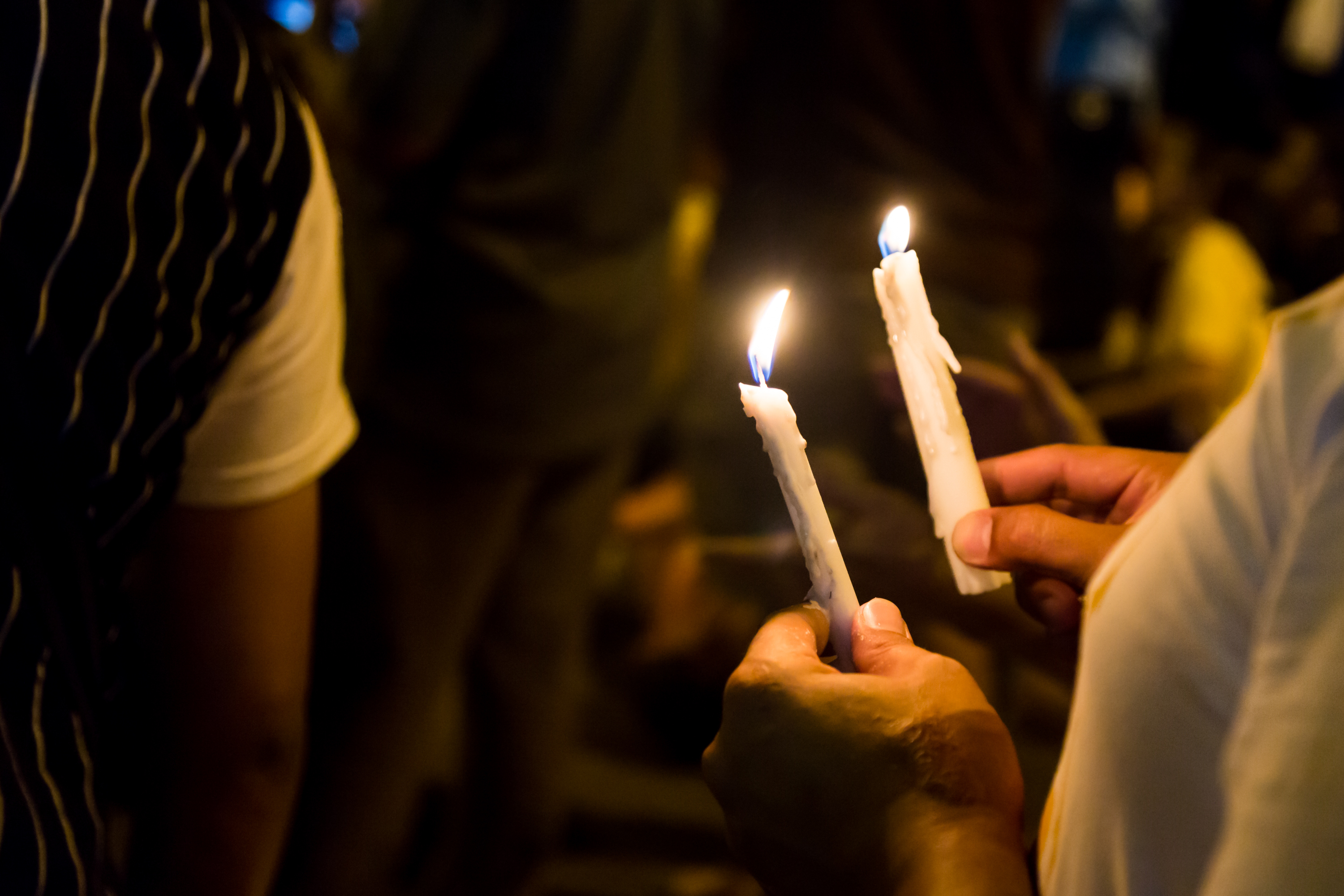 people holding memorial candles in the dark
