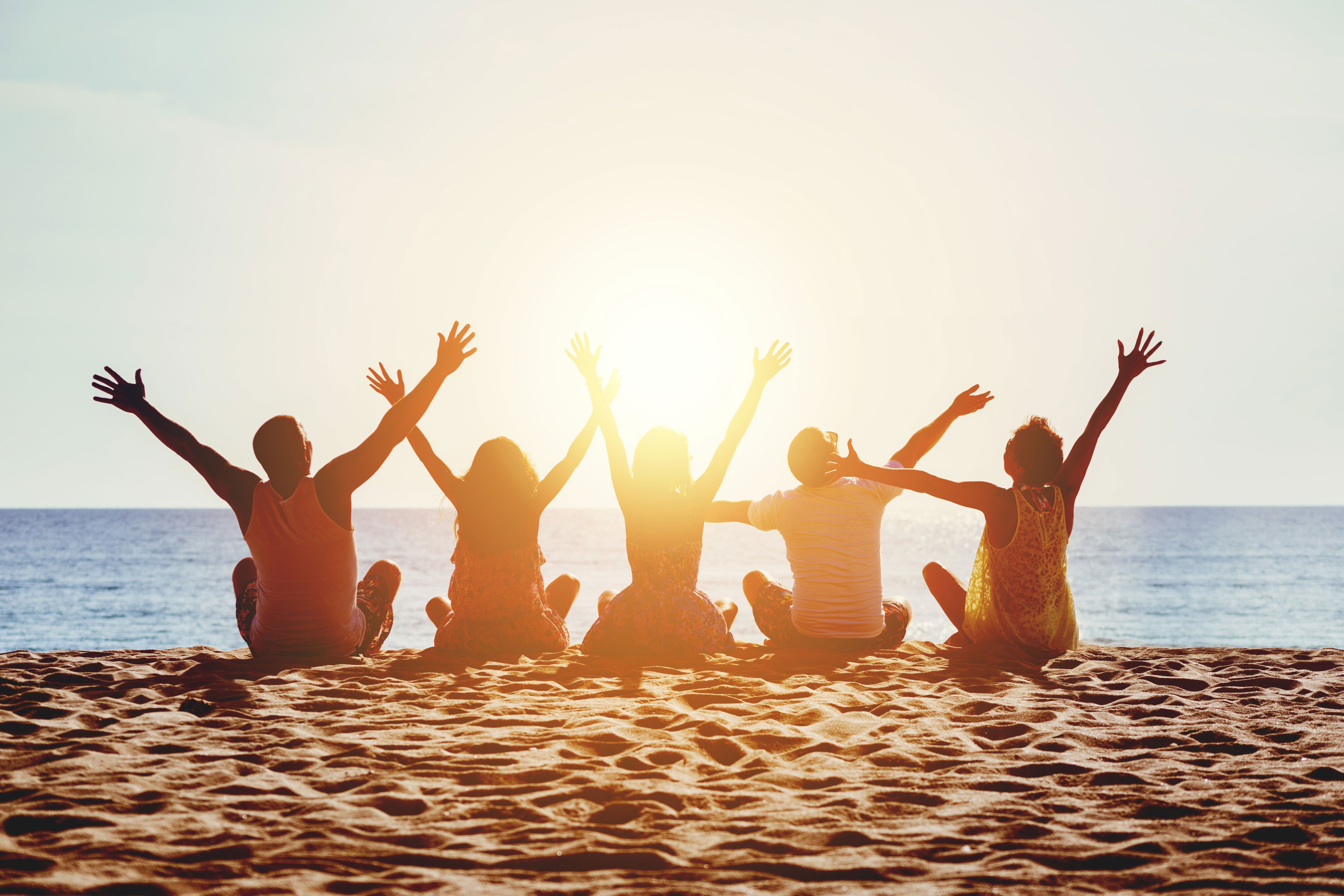 Group of friends sitting at the beach watching the sunset
