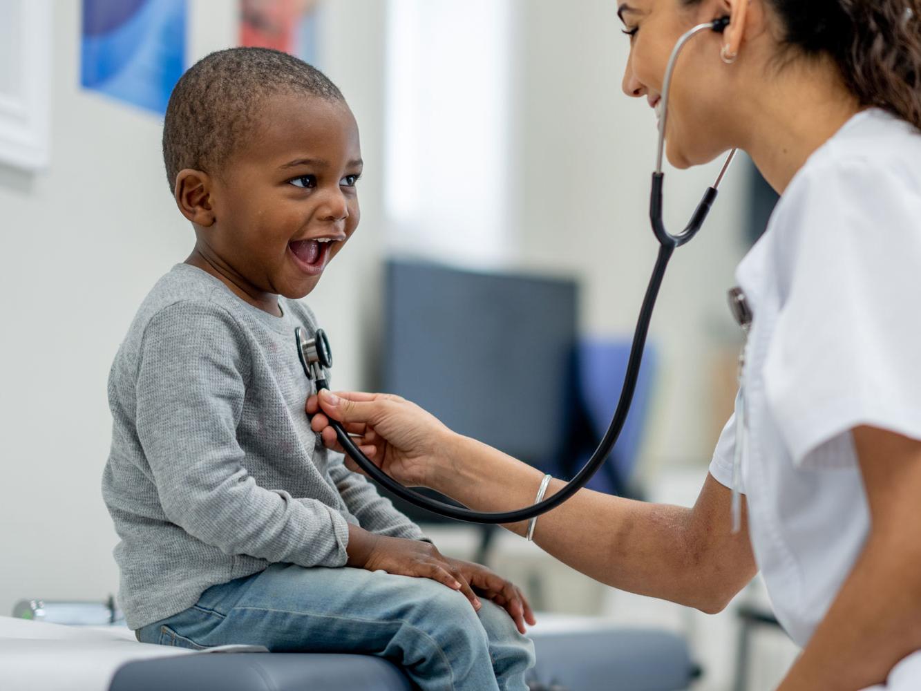 A pediatrician listens to a child's heartbeat