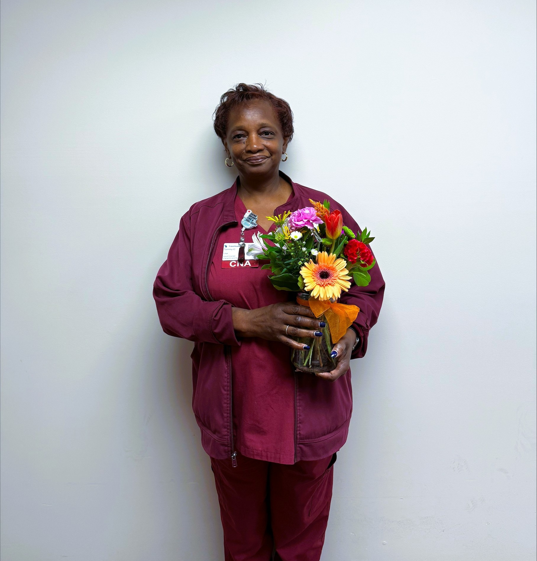 a woman on a gray wall holding a vase of flowers