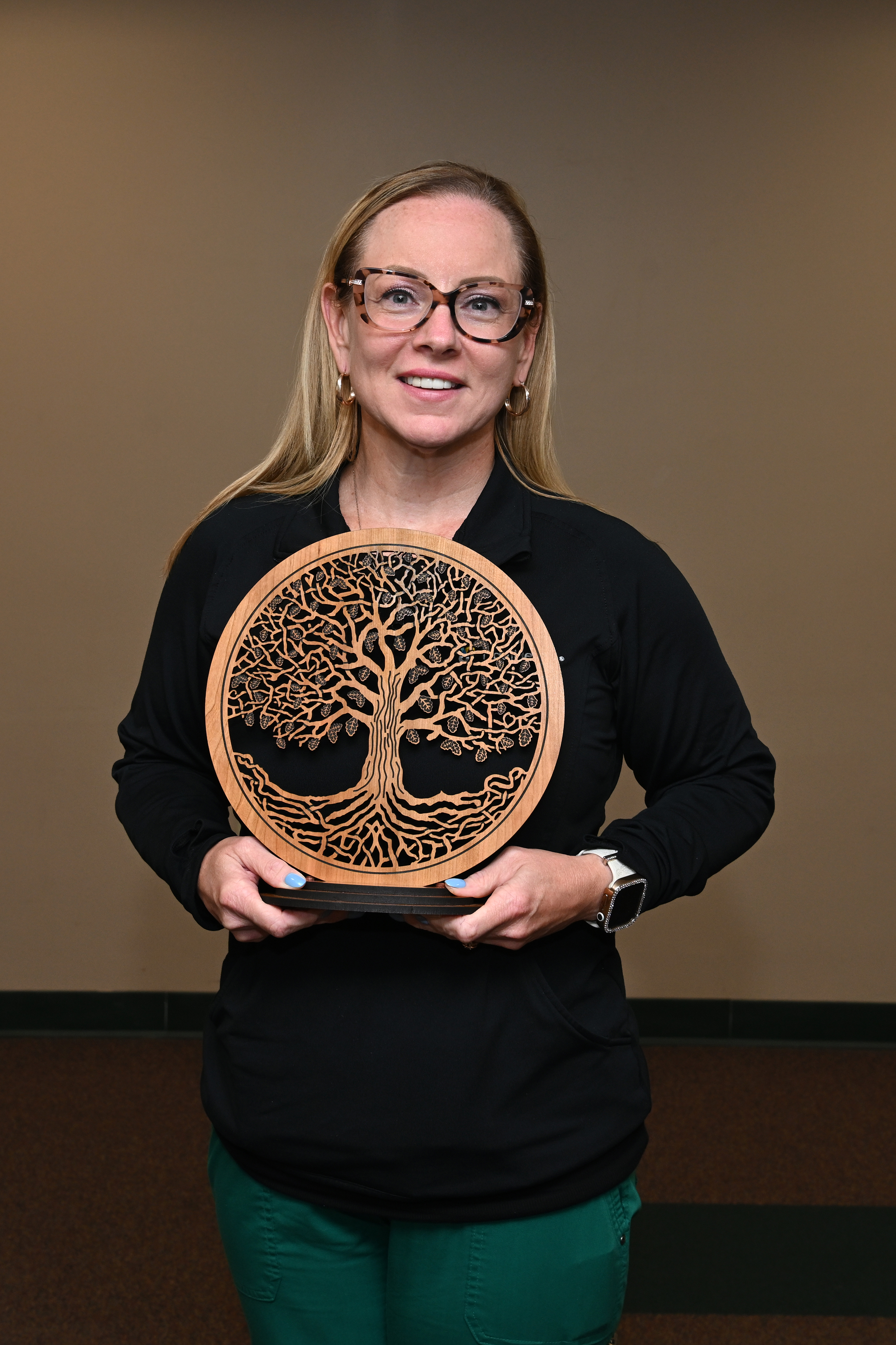 a woman holding a tree of life award in front of her.