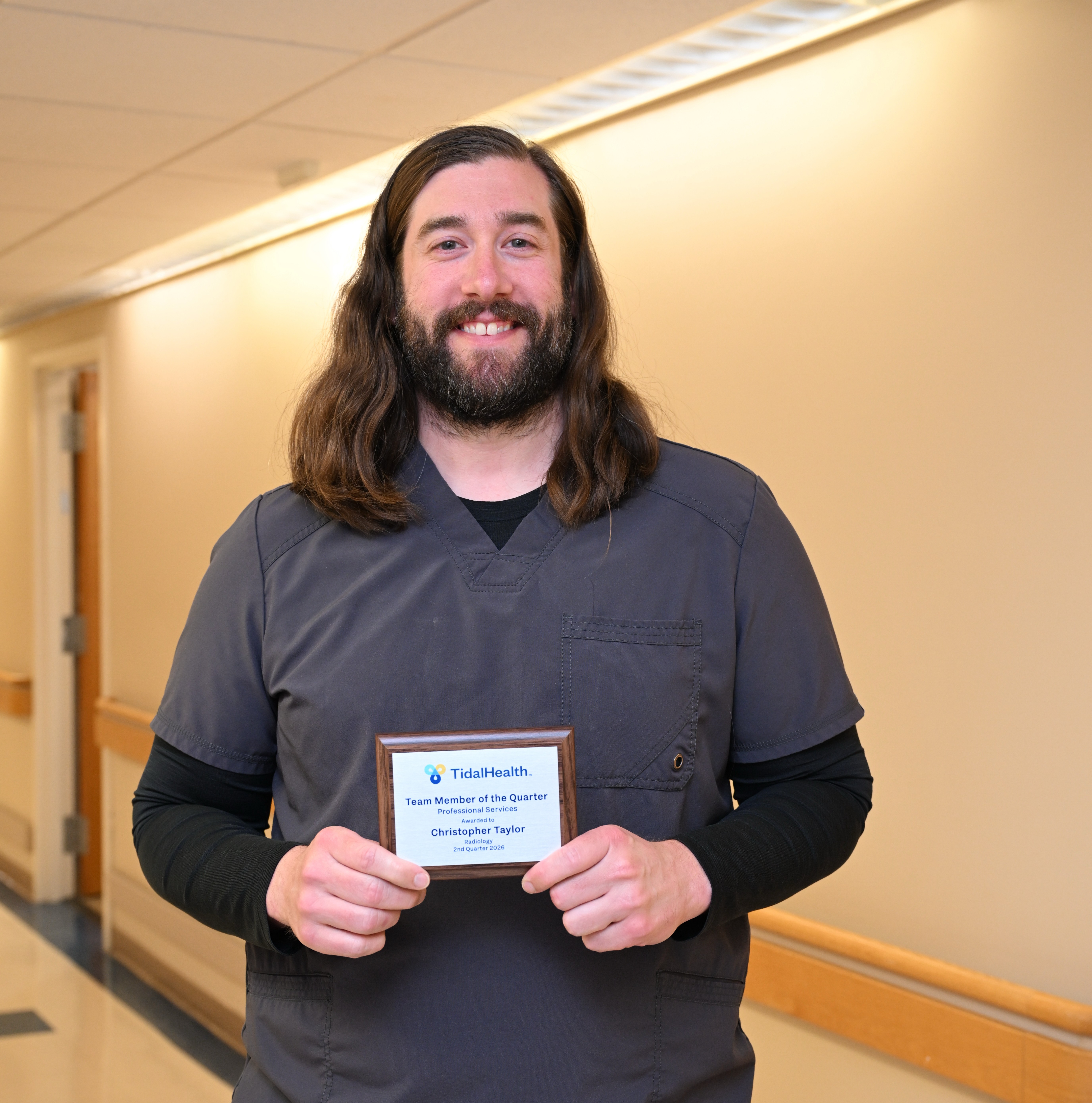 a man in gray scrubs holding an award