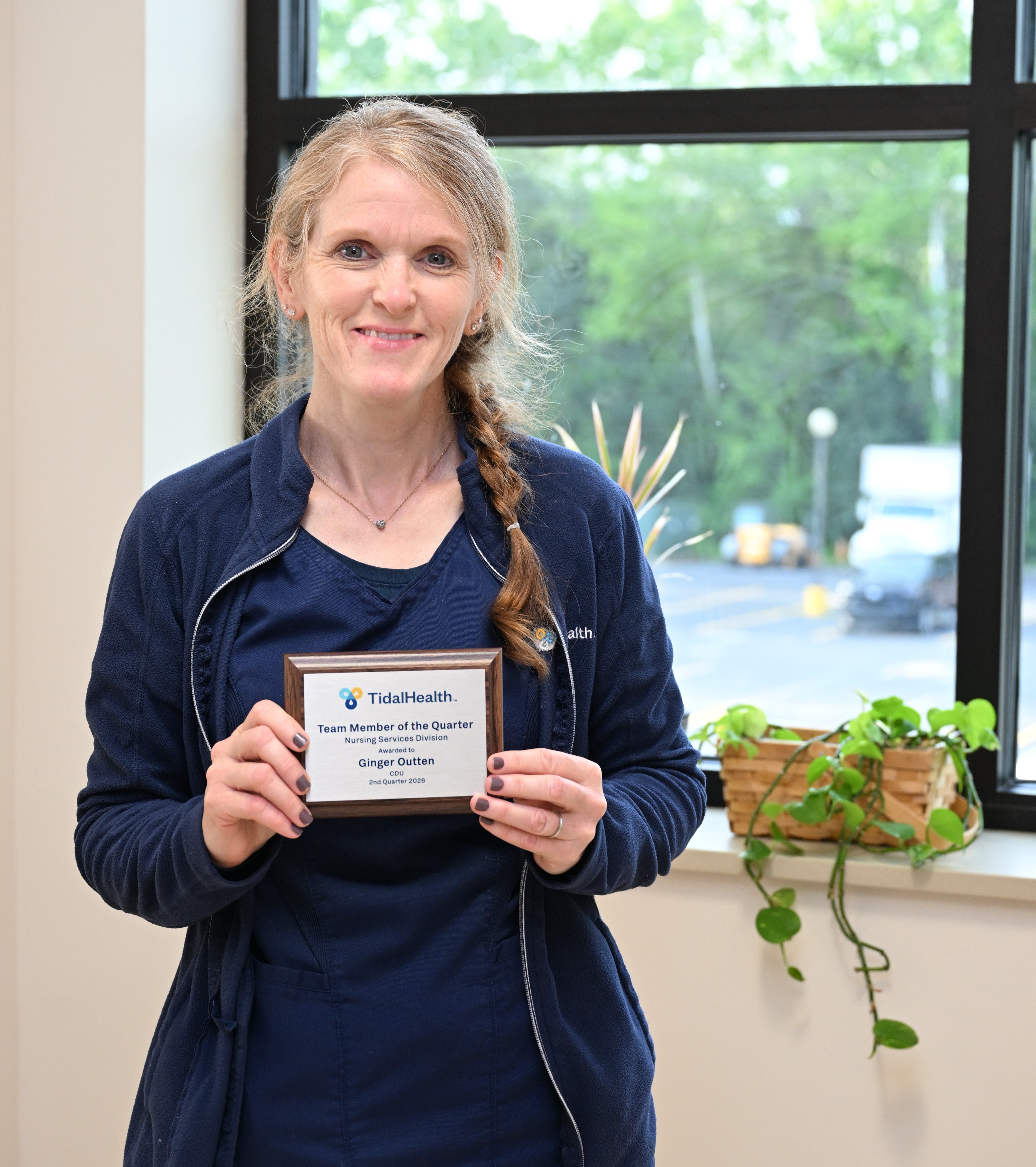 a nurse standing in front of a plant by a window