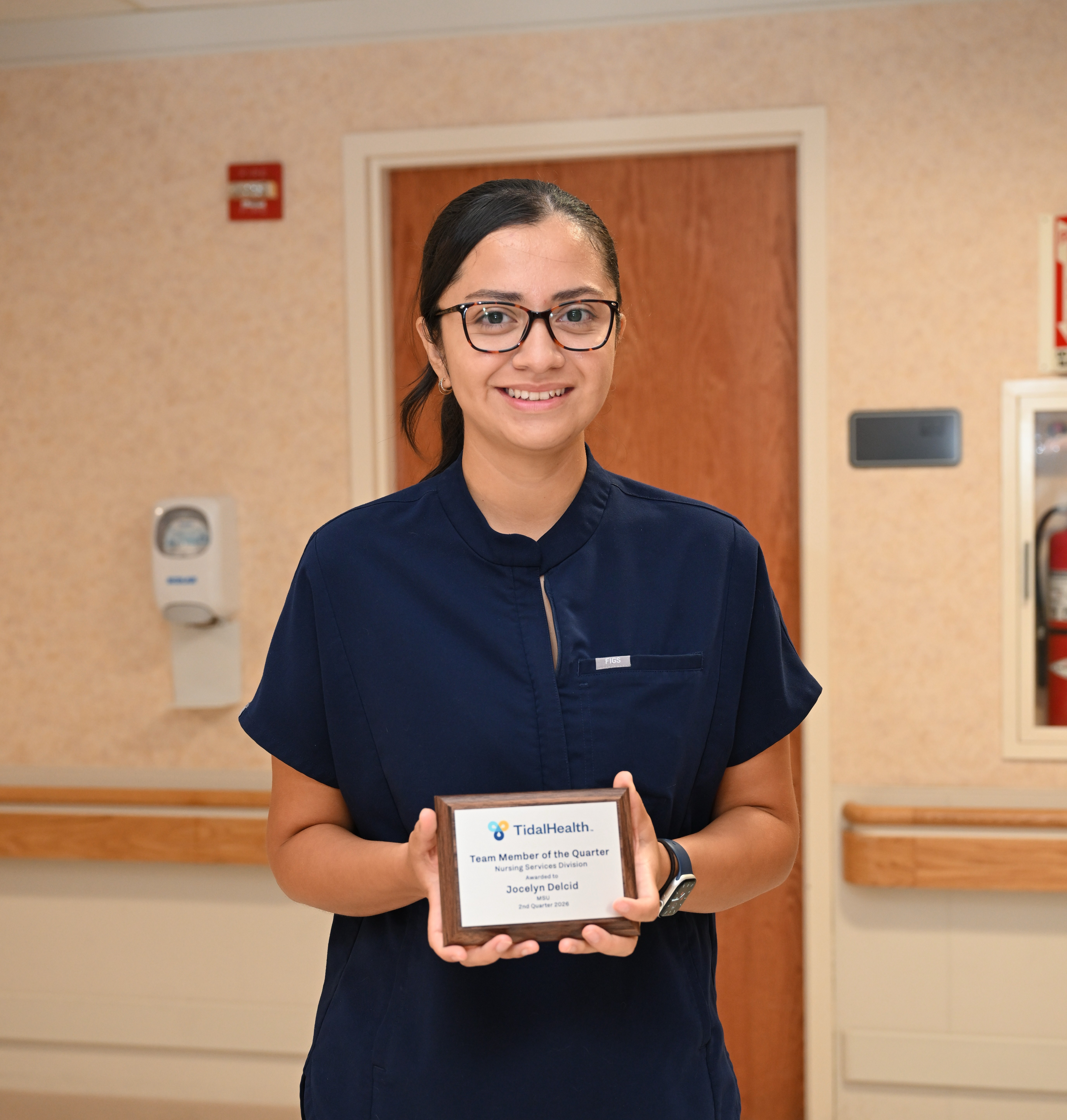 a nurse with glasses holding an award