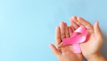 Hands holding a pink ribbon