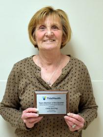 A woman in a brown shirt holding her award