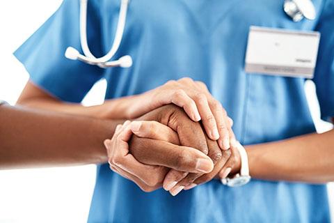 healthcare worker holds the hand of a patient