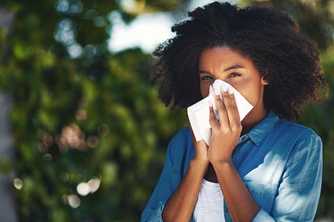 Women with seasonal allergies sneezes into a tissue