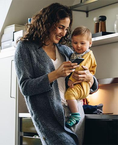 Mother holding child while looking at TidalHealth MyChart app on her phone