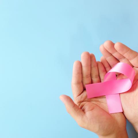 Hands holding a pink ribbon