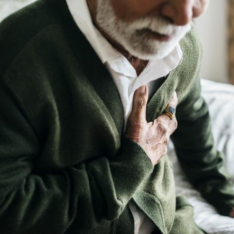 elderly man clutching chest having heart problems