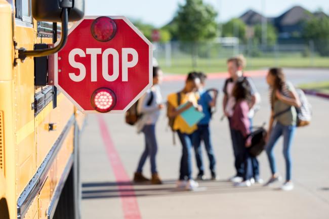 school bus with children crossing and flashing stop sign