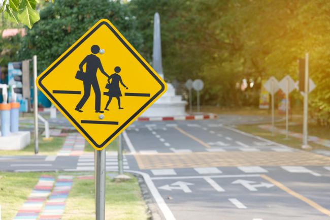 pedestrian crossing sign with a striped crosswalk in the background