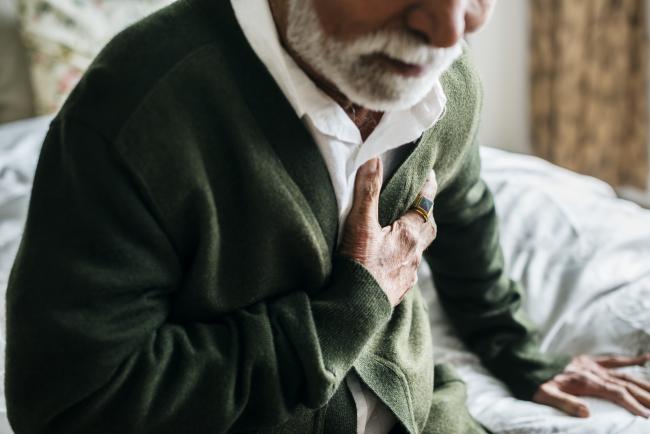 elderly man clutching chest having heart problems