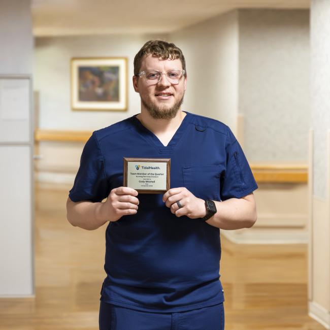 a man holding his award in front of him in a hallway