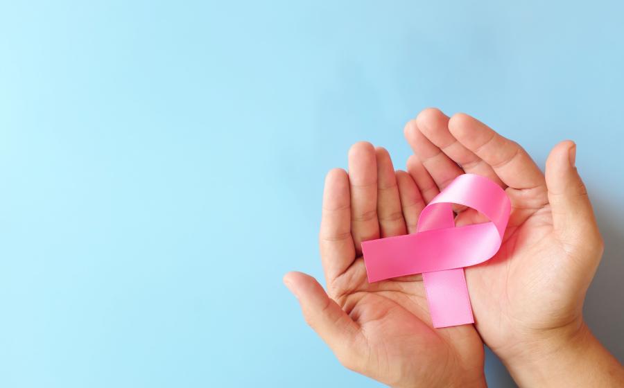Hands holding a pink ribbon