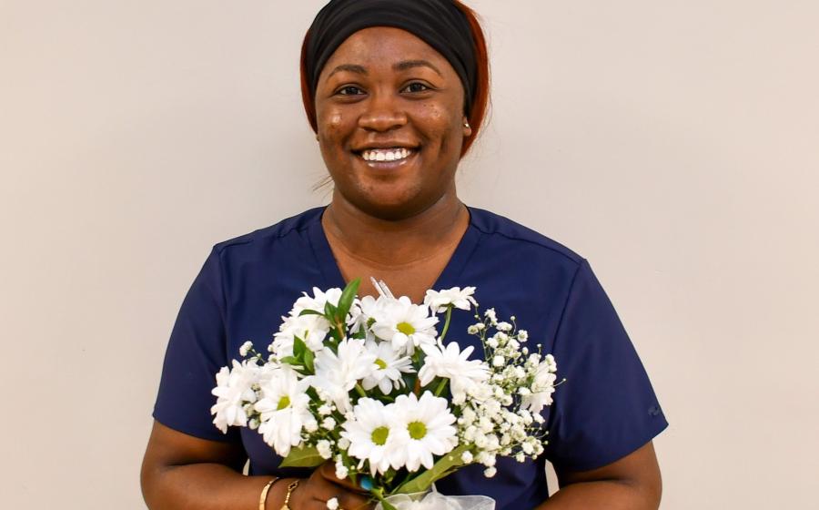 a smiling woman holding a vase of flowers