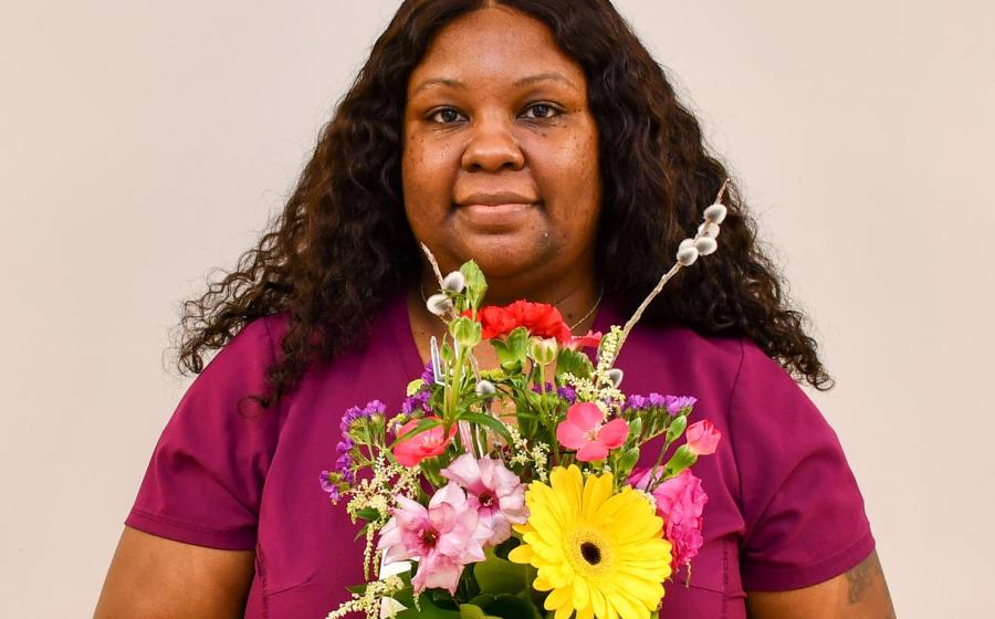 A woman holding a bouquet of assorted flowers in front of her