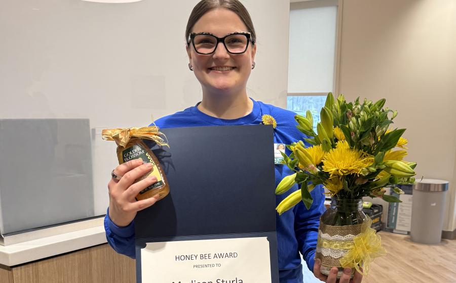 a woman holding an award, honey, and flowers