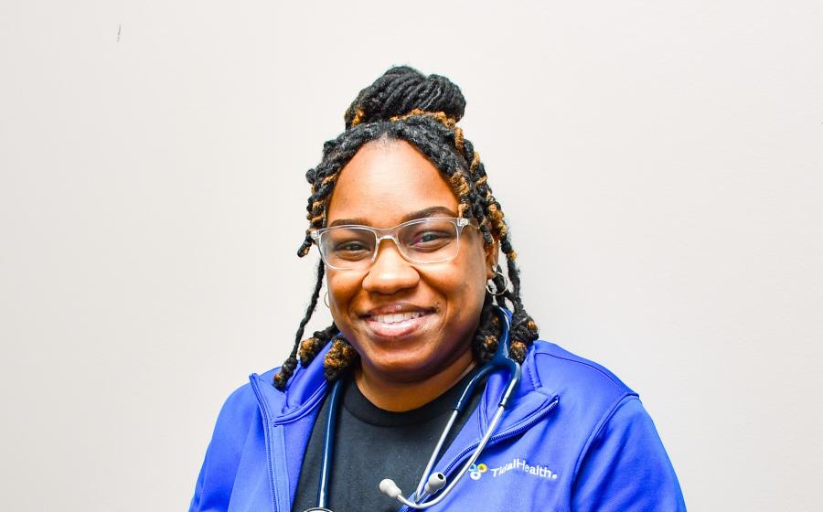 a woman smiling with braids and a blue jacket