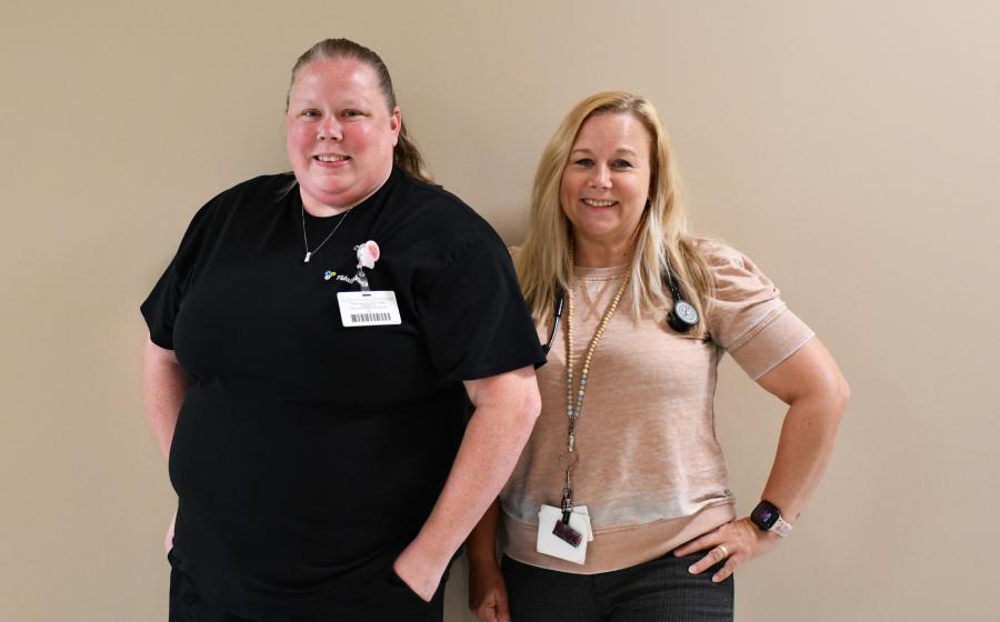 Ashley Crow and Danniell Hicks pose for a photo against a blank wall.