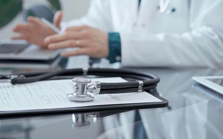 photo of doctor's hands, patient chart and stethoscope
