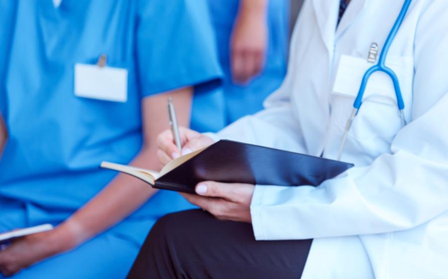 practitioner writing notes in a journal wearing stethoscope